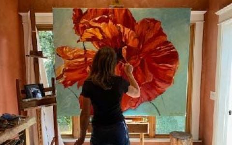 Heidi Love Larraz painting a red flower with her back to the camera, Seeking Beauty exhibition, 480x300